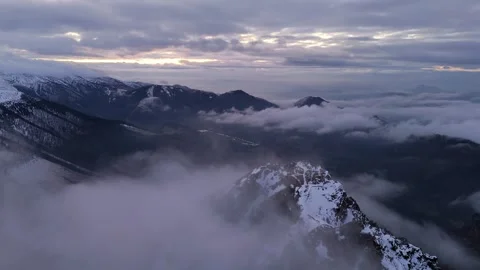 Aerial view of drone flight over snowy mountain peak at evening, winter, clouds 스톡 동영상 327594305
