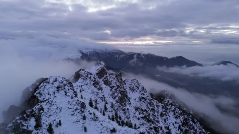 Aerial view of drone flight over snowy mountain peak at evening, winter, clouds Stock-Footage 327594401