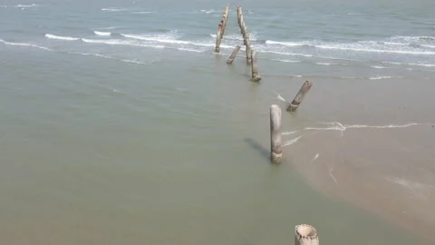 Aerial view of drone fly over the cement pillar from beach to the sea Stock Footage 153392631
