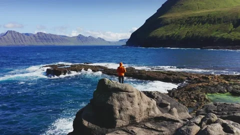 Aerial view of drone flying around a man,over rock beach,man resting in front of Video stock 155779932