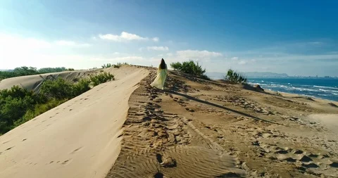 AERIAL View from a drone flying next to a happy woman in a dress on the dunes in Video stock 126899997