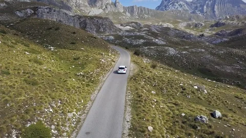Aerial view of drone flying over patched two lane with white car moving through Stock Footage 114316247