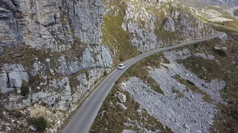Aerial view of drone flying over patched two lane with white car moving through Stock Footage 114316732
