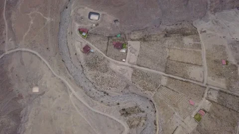 Aerial view of drone looking down a dry river between crops and country houses i Video stock 199632482