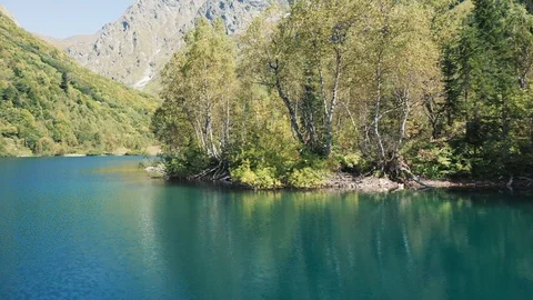 Aerial view; drone moving over mountain lake with torquoise water Stock Footage 120855712