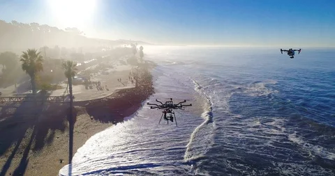 Aerial view of a drone orbiting two drones at the beach on a sunny day. 4K Stock Footage 87188545