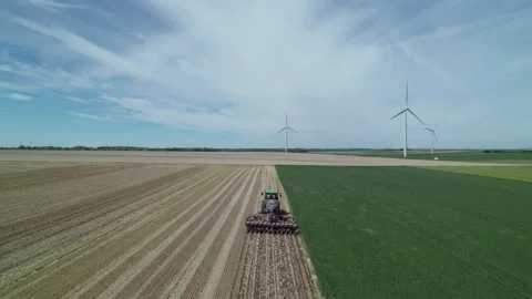 Aerial view by drone of tractor plowing the land in wind farm with windmills Stockbeeldmateriaal 166309846