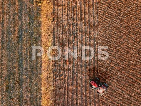Aerial view from a drone of a tractor at tillage in a farm land field Stock Photos