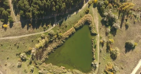 Aerial view from drone. Triangular shape of forest lake, among dirt roads Stock Footage 154543869