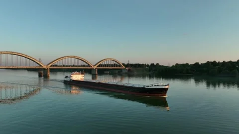 Aerial view. A dry cargo ship sails on the river at sunset near of big bridge. Stock Footage 234581911