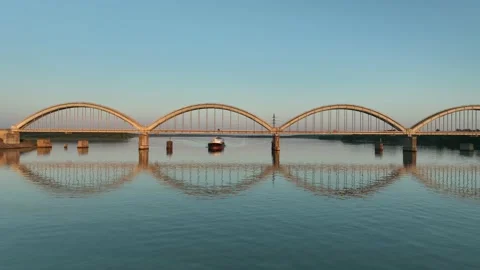 Aerial view. A dry cargo ship sails on the river at sunset near of big bridge. Stock Footage 234837111