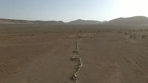 Aerial View of Dry Riverbed Winding Through Arid Desert Landscape Stock Footage 335719902