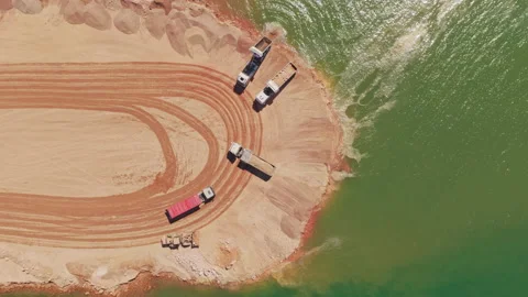 Aerial view of dump trucks dumping sand into water Stock-Footage 345007299