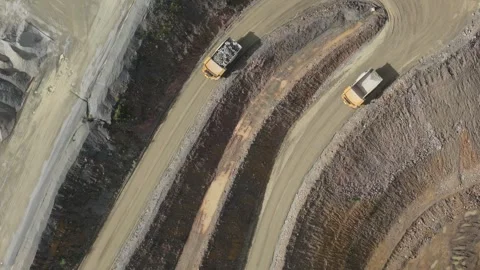 Aerial view of dump trucks transporting ore in an open pit mine Видео 343844639