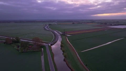 Aerial view of Dutch windmill casting shadow on blooming tulips at dawn Stock Footage 313361715