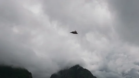 Aerial view of an eagle flying low over a cloud-covered mountain landscape in Stock Footage 289636960
