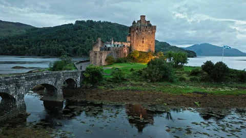 Aerial view of Eilean Donan Castle lit up at night with long arched bridge. Stock Footage 283496274
