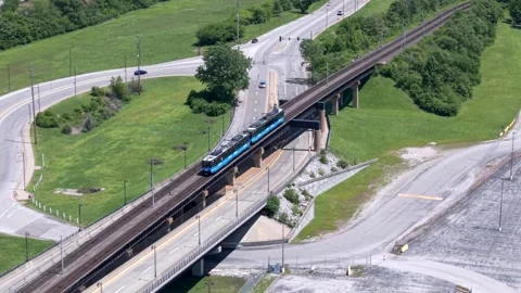 Aerial View of Electric Commuter Train Passing Through Suburban Countryside on Stock Footage 341881490