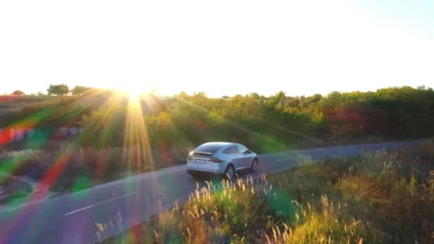 Aerial view of electrical car speeding on countryside road with beautiful sun Video stock 295264684