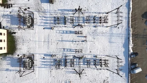 Aerial view of electrical substation with snow-covered ground, showing power Видео 335884276