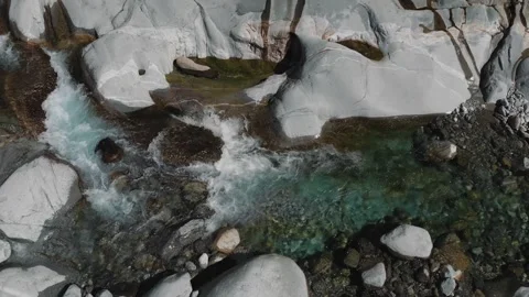 Aerial view of emerald mountain stream among white boulders and bare branches Stock Footage 346177724