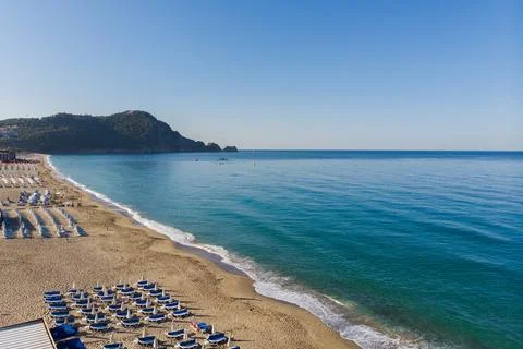 Aerial view of empty beach with rows of sun loungers, golden sand, calm Stock Photos