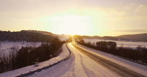 Aerial view of an empty frozen road crossing a frozen river during a sunset Stock Footage 105583645