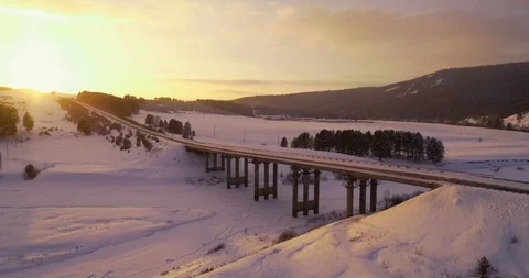 Aerial view of an empty frozen road crossing a frozen river during a sunset Stock Footage 105583771
