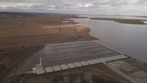 An aerial view of an empty marina with floating docks extending into a calm Stock Footage 303416292