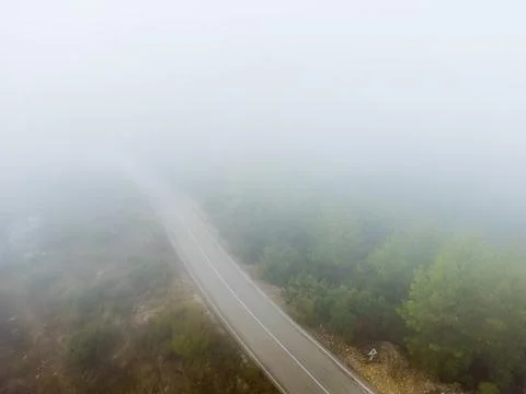 Aerial view of an empty mountain road disappearing into fog Stock Photos