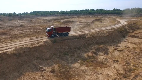 Aerial view of empty red dump truck for sand delivery moving on the sand track Vídeos de archivo 104733052