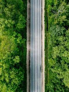 Aerial view of empty road going through green forest. Stock Photos