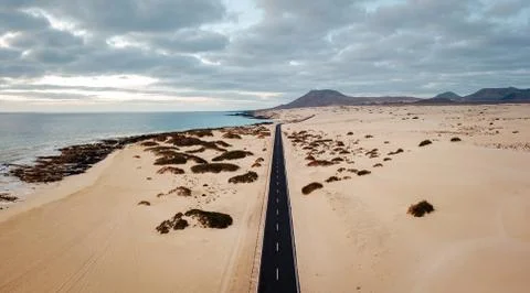 Aerial view of an empty road through the dunes at the sunrise with copy space Stock Photos