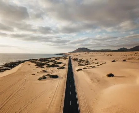 Aerial view of an empty road through the dunes at the sunrise with copy space Stock Photos