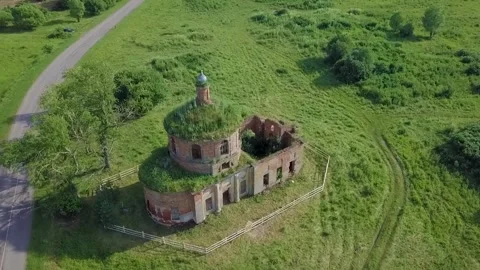 Aerial view of empty, rundown circular brick building in green field, evoking Vídeos de archivo 277294502