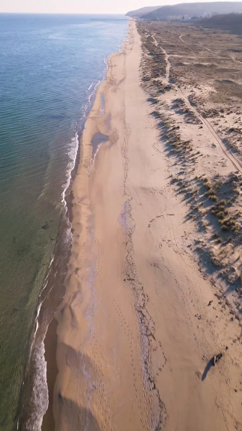 Aerial view of empty sandy beach and calm sea under clear blue sky. Peaceful Stock Footage 324852063