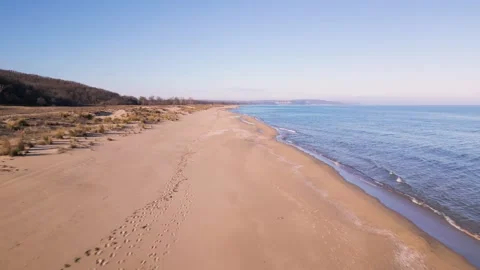 Aerial view of empty sandy beach and calm sea under clear blue sky. Peaceful coa Stock-Footage 325740728