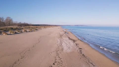 Aerial view of empty sandy beach and calm sea under clear blue sky. Peaceful coa 库存影片 325740771