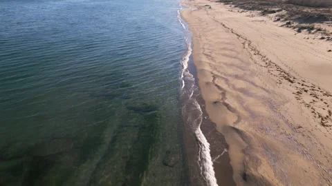 Aerial view of empty sandy beach and calm sea under clear blue sky. Peaceful coa Stock Footage 325740820