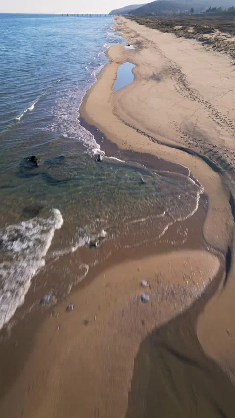 Aerial view of empty sandy beach and calm sea under clear blue sky. Peaceful coa Vidéo 325740834
