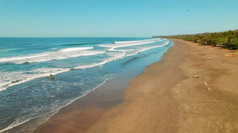 Aerial view of empty sandy beach with rolling waves under blue sky in Costa Rica Stock Footage 341452574