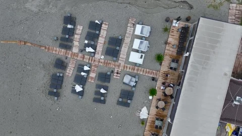 Aerial View: Empty sunbeds on a sandy shore offer a calm and inviting setting Stock Footage 296052850