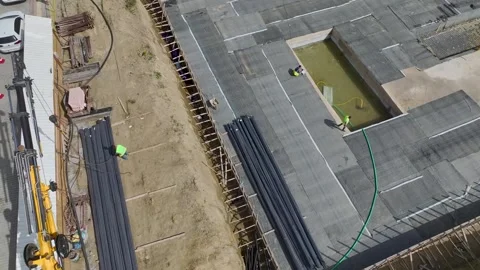 Aerial View: Engineers oversee the insulation of building foundations while Stock Footage 296095292