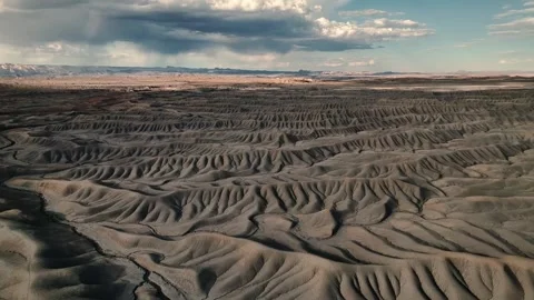 Aerial view of eroded badlands and desert ridges under a cloudy sky. Stock Footage 335212876