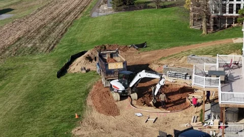 Aerial view of excavator digging backyard pool at suburban American home with Video stock 333701307