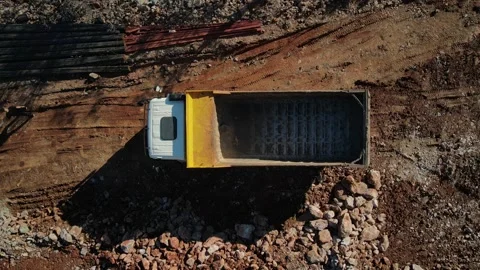 An aerial view of an excavator loading heavy rocks and soil into a truck.  Stock Footage 302023799