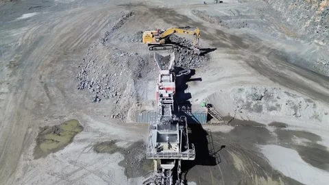 Aerial view of excavator loading rocks into conveyor system Stock Footage 332722281