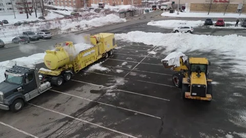 Aerial view of an excavator loading snow into a snow melting machine. Stock Footage 271654172