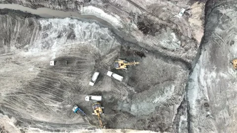 Aerial view of an excavator loading soil into trucks on a huge construction site Stock Footage 232586509