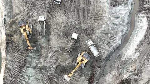 Aerial view of an excavator loading soil into trucks on a huge construction site Stock Footage 232587749